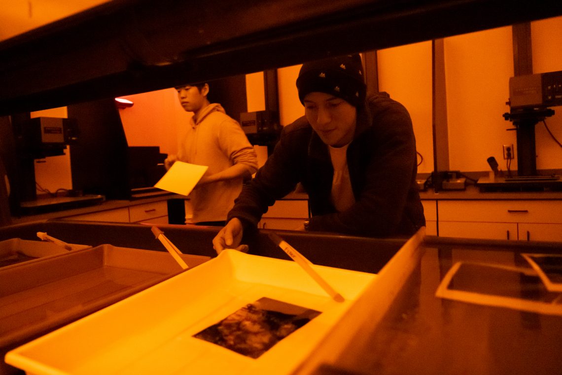 Students working in photography darkroom.